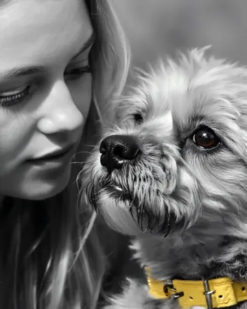 Une femme et son petit chien au collier jaune, tout près l’un de l’autre, en noir et blanc